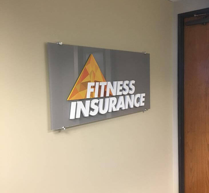 Floating acrylic brand panel with dimensional logo for Fitness Insurance in Centennial, CO — interior lobby sign installed by Vision Visual Signs