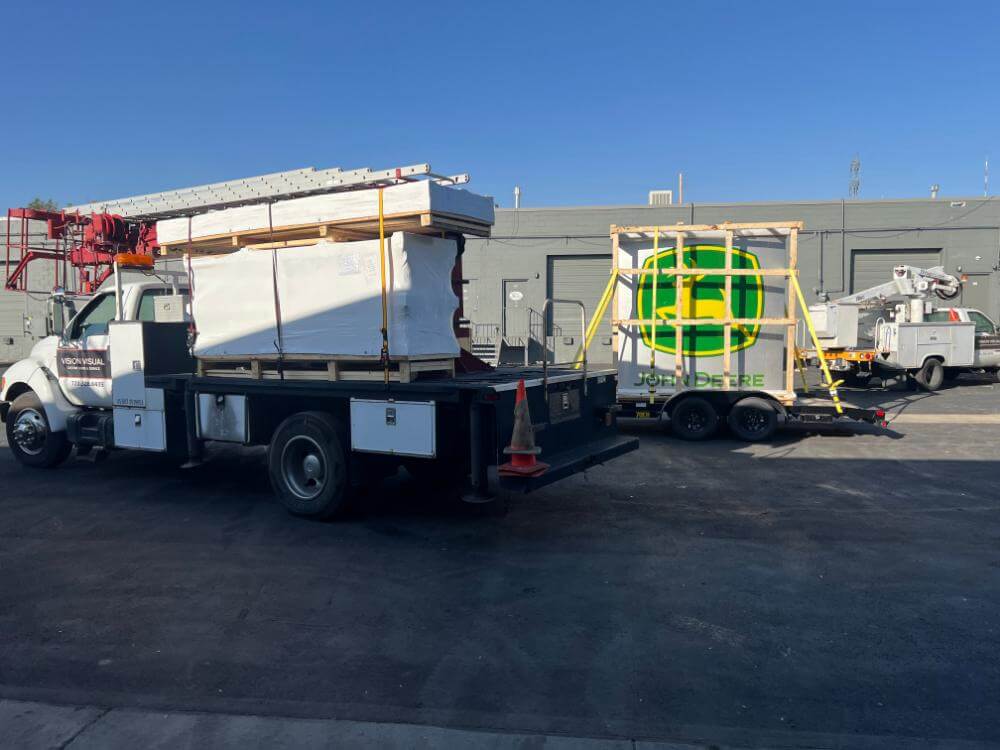 vision visual crane and bucket trucks loaded with John Deere pole sign at Golden, CO